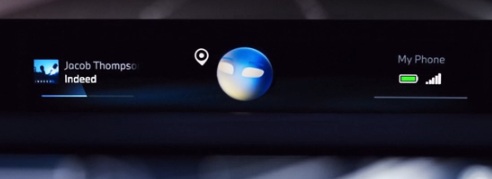 Das Bild zeigt den Bildschirm eines BMW iX3 im Innenraum, während das Auto durch einen Tunnel fährt. Im oberen Teil des Bildes ist der Titel „Hey BMW“ zu sehen. Darunter befinden sich verschiedene Benachrichtigungen und Informationen, wie zum Beispiel ein Anruf von „Jacob Thompson“ über „Indeed“ und eine Standortanzeige. Auf der rechten Seite sind das Akku- und Empfangssymbol eines Mobiltelefons abgebildet.
