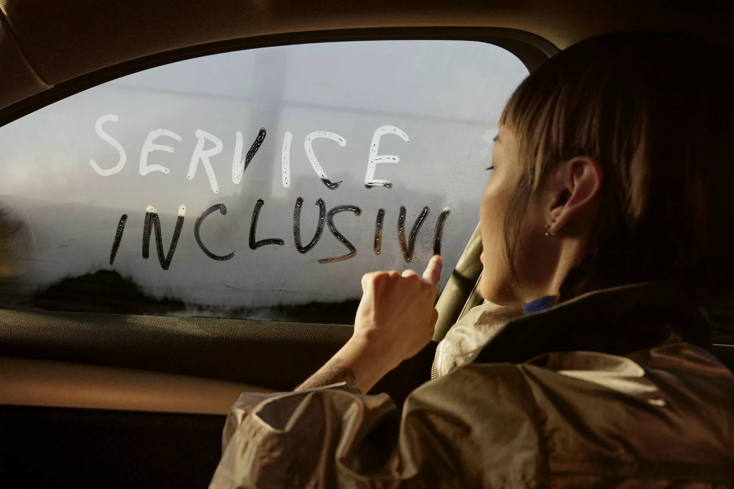 Person schreibt "SERVICE INCLUSIVE" in beschlagene Autoscheibe.