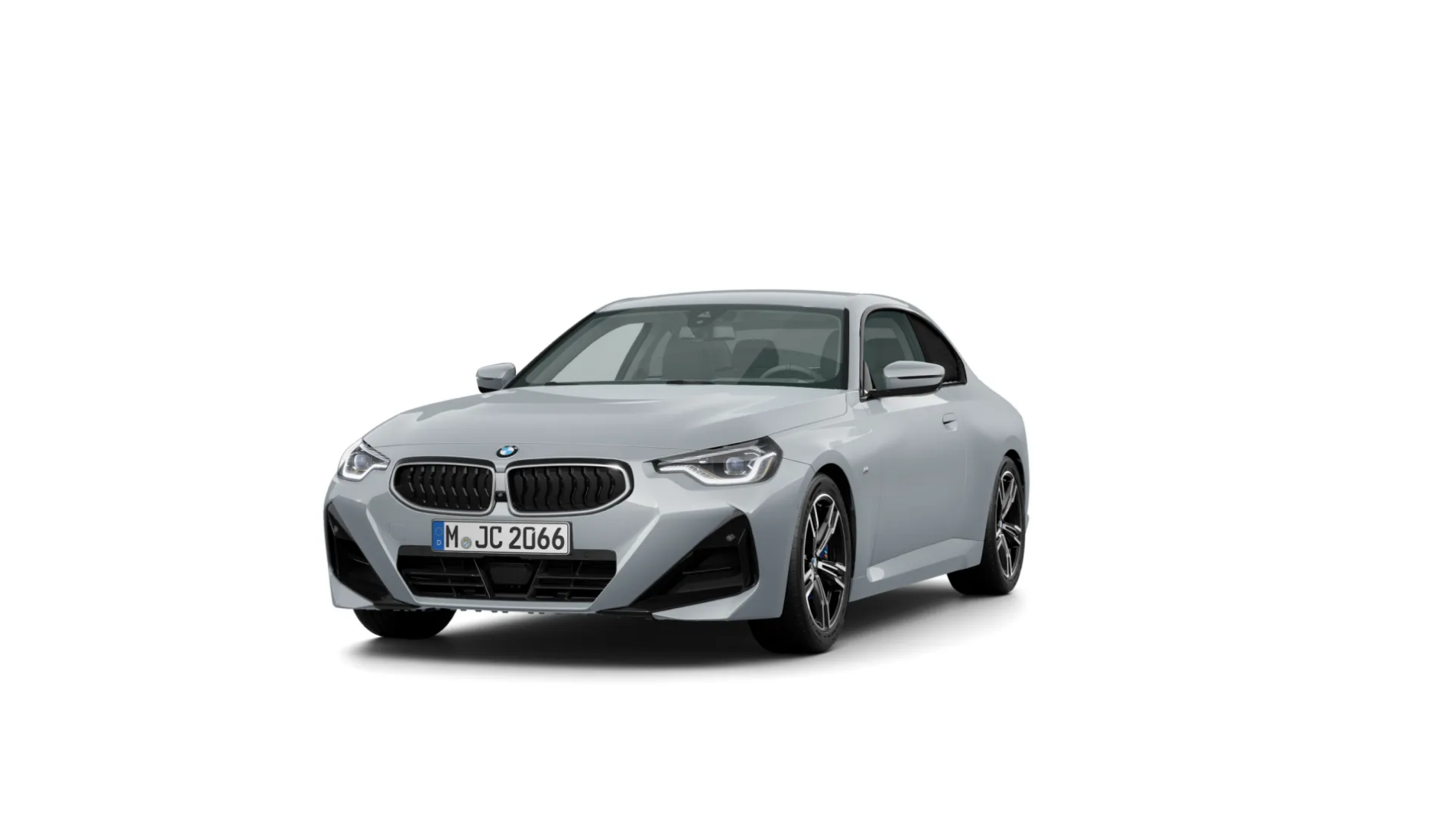 Das Bild zeigt einen silbergrauen BMW 2er-Reihe Coupé. Das zweitürige Auto steht schräg von vorne auf einem weißen, leeren Hintergrund. Das Kennzeichen "M JC 2066" ist auf der vorderen Stoßstange zu sehen.