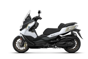Ein großer, weißer und schwarzer Maxi-Scooter von BMW, schräg von der Seite fotografiert vor einem weißen Hintergrund. Der Roller hat eine große Windschutzscheibe, goldene oder bronzefarbene Felgen und goldene Akzente auf der weißen Seitenverkleidung, unter anderem mit der Aufschrift "GT".
