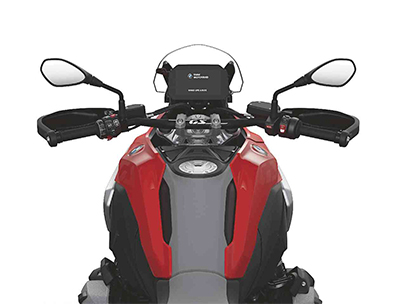  Das Bild zeigt die Sicht aus der Fahrerperspektive der BMW R 1300 GS. In der Mitte befindet sich das digitale Cockpit mit einem Bildschirm. Links und rechts davon sind die Lenkergriffe mit Spiegeln und den Bedienelementen zu sehen. Der obere Teil des Tanks ist in den Farben Rot-Orange und Grau gehalten.