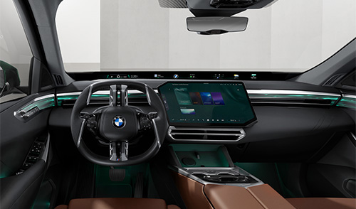 Moderner Innenraum des neuen BMW X5 mit großem Touchdisplay, digitaler Instrumentenanzeige, grüner Ambientebeleuchtung und braunen Sitzen.