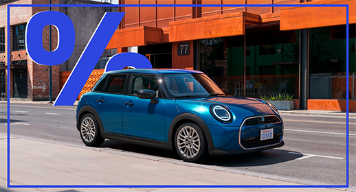  Dieses Bild zeigt einen blauen MINI Cooper 5-Türer, der auf einer Stadtstraße fährt. Das Auto hat ein schwarzes Dach. Über dem Auto schwebt ein großes, blaues Prozentzeichen (%).