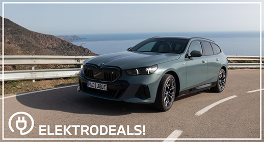 Dreiviertel-Vorderansicht eines graugrünen BMW i5 Touring Elektro-Kombis mit Kennzeichen 'MDI 380E', parkend auf einer Küstenstraße. Mit 'Elektrodeals!'-Logo."