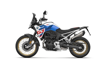  Ein sportliches Adventure-Motorrad von BMW in den Farben Weiß, Blau und Rot, angelehnt an das BMW M-Design. Es steht schräg von der Seite vor einem weißen Hintergrund. Es hat eine Windschutzscheibe, goldene Speichenfelgen und einen Enduro-Look.