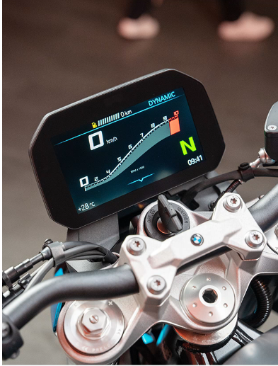 Nahaufnahme eines hochauflösenden, digitalen Motorrad-Displays, das in ein Cockpit mit silbernen Gabelbrücken und schwarzem Lenker eingebettet ist. Das Display ist aktiv und zeigt den Fahrmodus „DYNAMIC“ oben rechts. Die aktuelle Geschwindigkeit von 0 km/h ist zentral in einer digitalen Anzeige zu sehen, flankiert vom großen, grünen "N" für den Leerlauf und der Uhrzeit 09:41. Ein weißer Balken visualisiert die Drehzahl (RPM) mit einem roten Bereich bei hohen Drehzahlen. Weitere Informationen umfassen die Außentemperatur von +28 °C links unten und eine Tankuhr.