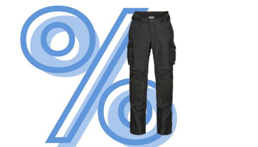 Das Bild präsentiert vor einem ebenfalls von einem großen, hellblau stilisierten Prozentzeichen (%) dominierten weißen Hintergrund eine schwarze Motorradhose im Adventure- oder Rallye-Stil. Die Hose ist aus Textilmaterial gefertigt und verfügt über Taschen an den Oberschenkeln (Cargo-Taschen), was auf ihre Eignung für Offroad- und Tourenfahrten hindeutet. Sie hat ein schlichtes, robustes Design ohne auffällige Grafiken.
