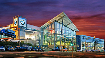 BMW Rhein Standort Heilbronn Modernes BMW Rhein Autohaus bei Dämmerung mit beleuchteten Schaufenstern und geparkten BMWs