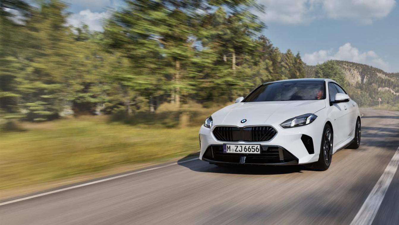  Ein weißes BMW 216 Gran Coupé fährt auf einer kurvigen Straße, die durch eine Wald- und Berglandschaft führt. Das Auto ist leicht von vorne und rechts zu sehen und nimmt den größten Teil der linken Bildhälfte ein. Am unteren Rand des Bildes befindet sich ein Textfeld, das folgende technische Daten enthält: WLTP Energieverbrauch kombiniert: 5,9 l/100km; WLTP CO₂-Emissionen kombiniert: 134 g/km; CO₂-Klasse: D; Leistung: 90 kW (122 PS); Hubraum: 1.499 cm³; Kraftstoff: Benzin. Der Text endet mit dem Hinweis, dass die Abbildung Sonderausstattungen zeigt. Das Kennzeichen des Wagens lautet "M ZJ 6656".