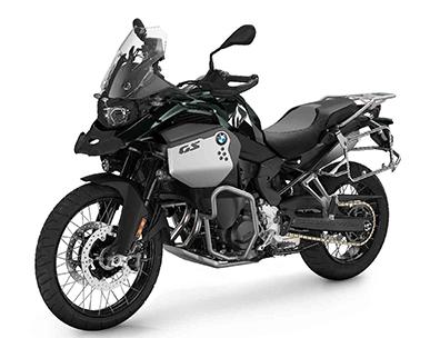  Auf dem Bild ist eine BMW F 900 GS Adventure abgebildet, ein großes, schwarzes und graues Motorrad, das auf einem weißen Hintergrund steht.  Das Motorrad ist in einem hellen, sonnigen Licht und steht seitlich zur Kamera. Es ist sauber und glänzt, als wäre es brandneu.