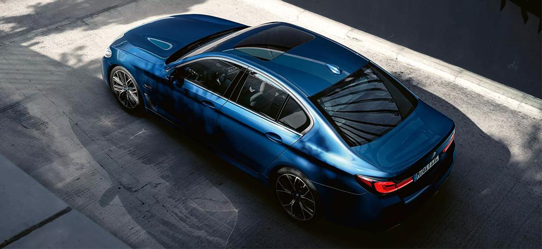 Dunkelblaue BMW Limousine von oben auf gepflasterter Fläche.