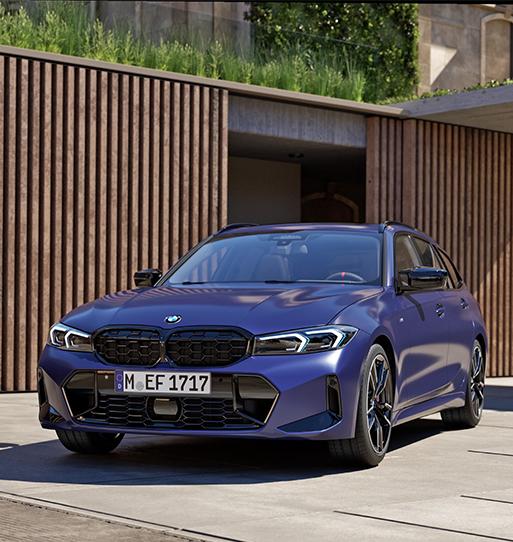 Blauer BMW M340i xDrive Touring in sportlicher Frontansicht vor moderner Architektur.