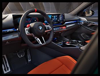 Das Interieur des BMW M5 Touring bietet ein hochmodernes Cockpit mit dem BMW Curved Display, M-spezifischen Grafiken und einer luxuriösen Lederausstattung in hellen Farben.
