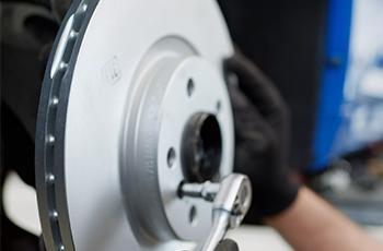 Nahaufnahme einer BMW Bremsscheibe während der Wartung in der Werkstatt.