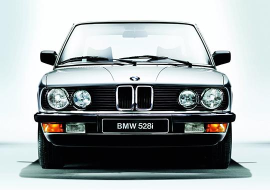 Klassischer BMW 528i in frontaler Ansicht vor hellem Hintergrund.