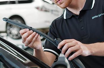 BMW Servicetechniker montiert ein Wischerblatt an der Windschutzscheibe.