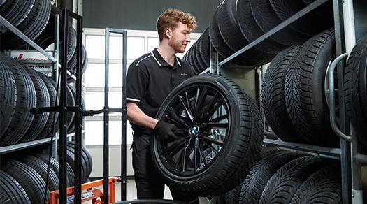 BMW Servicetechniker lagert ein BMW Komplettrad in einem Reifenregal ein.