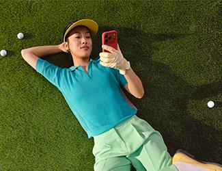 „Frau liegt entspannt auf einer Rasenfläche und nutzt ihr Smartphone.“