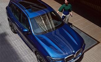 Blauer BMW aus der Vogelperspektive mit einer Frau neben dem Fahrzeug.