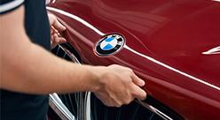 BMW Servicetechniker arbeitet an der Front eines roten BMW.