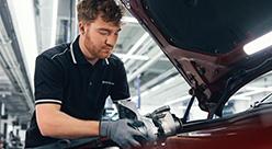BMW Servicetechniker führt Arbeiten im Motorraum eines Fahrzeugs durch.