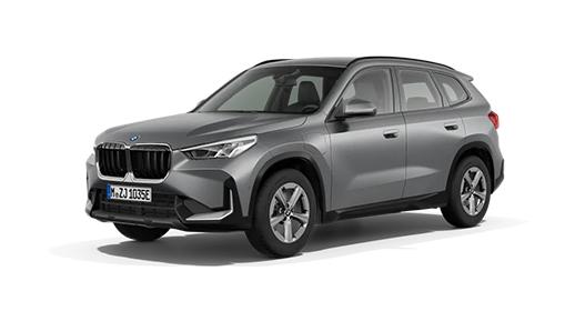 Das Bild zeigt einen grauen BMW X1 Plug-in-Hybrid. Die Aufnahme ist von schräg vorne gemacht, das Auto steht auf einem weißen Hintergrund. Es hat die erhöhte Bauform eines SUV. Die Front ist mit der typischen BMW-Doppelniere und breiten Scheinwerfern gestaltet. Die Räder sind mit schlichten, silberfarbenen Felgen ausgestattet. An der Seite sind die Plug-in-Hybrid-typischen Ladeanschlüsse zu sehen.