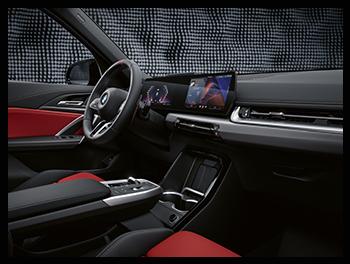 Moderner Innenraum mit roten Sportsitzen, dem flachen „BMW Curved Display“ und einer schwebenden Mittelkonsole.