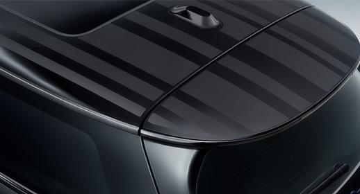 Nahaufnahme des Fahrzeugdachs und Dachspoilers der MINI Paul Smith Edition mit dem für den Designer charakteristischen Streifenmuster in matten und glänzenden Schwarztönen.
