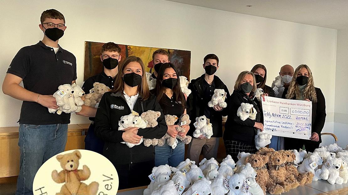 Eine Gruppe junger Menschen, viele mit Plüschtieren und Masken, präsentieren einen Spendenscheck über 5.000 € für "Hilfe durch Sport e.V.".