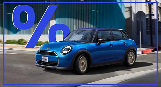  Dieses Bild zeigt einen blauen MINI Cooper 5-Türer, der auf einer Stadtstraße fährt. Das Auto hat ein schwarzes Dach. Über dem Auto schwebt ein großes, blaues Prozentzeichen (%).