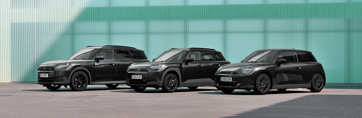 MINI Modellfamilie Dieses breitformatige Werbebild zeigt drei verschiedene schwarze MINI-Modelle, die nebeneinander auf einem asphaltierten Platz stehen. Von links nach rechts sind ein größerer MINI Countryman, ein kompakterer Fünftürer (der neue MINI Aceman) und der klassische MINI Dreitürer zu sehen. Alle Fahrzeuge glänzen in tiefem Schwarz und stehen vor einer modernen Architekturkulisse mit einer helltürkisen, geriffelten Glasfassade. Die Szene wirkt durch das klare Tageslicht und die kühle Farbkombination aus dem Türkis des Hintergrunds und dem Schwarz der Autos sehr urban und stylisch.