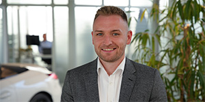 Mitarbeiterportrait von einem Mann in einem grauen Anzug in einem Autohaus